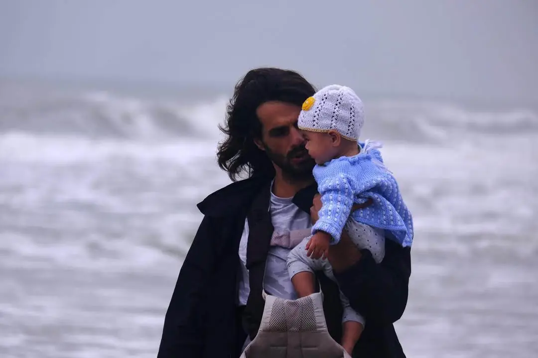 Viktor holding his daughter near the sea