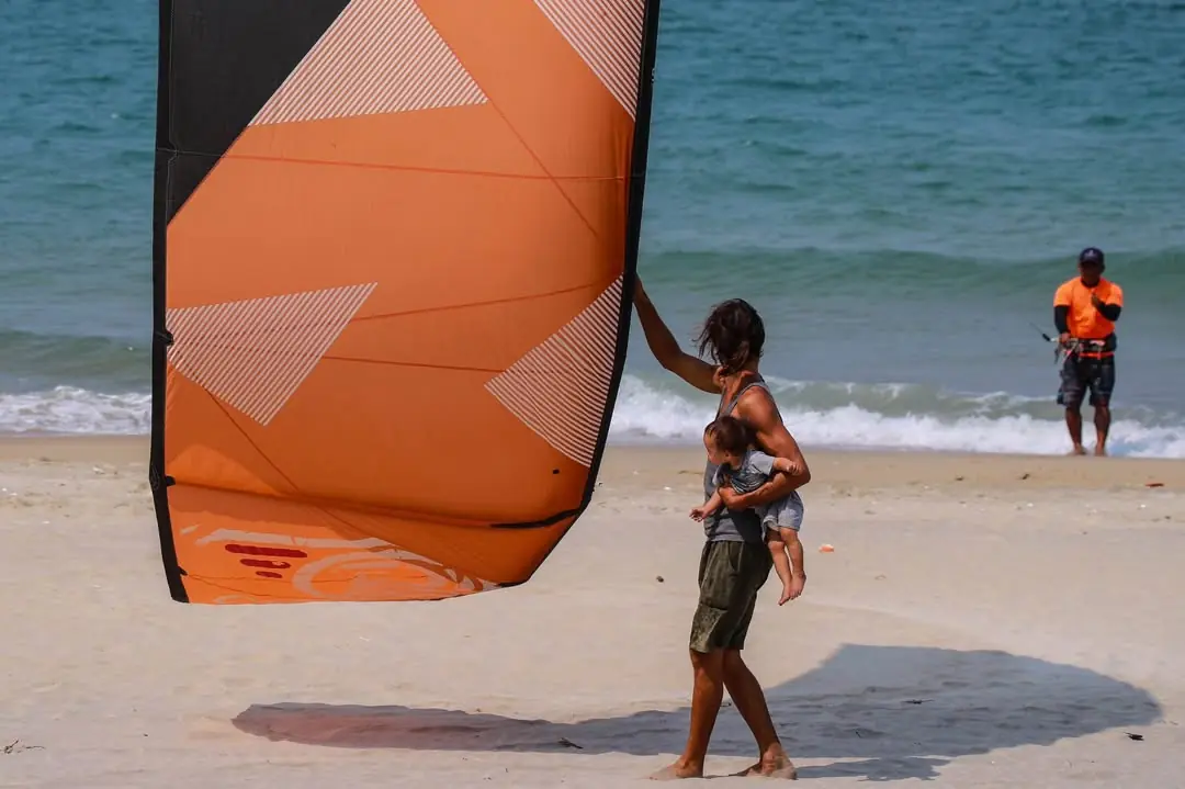 Viktor assisting a kite launch while holding his daughter